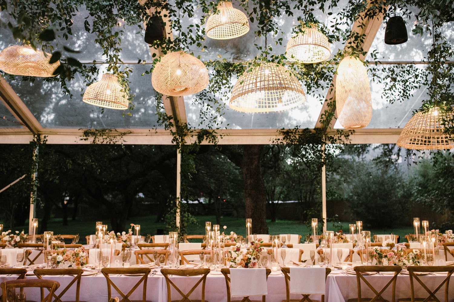 Rattan lanterns, white tablecloths, and peach flowers for an evening dinner reception