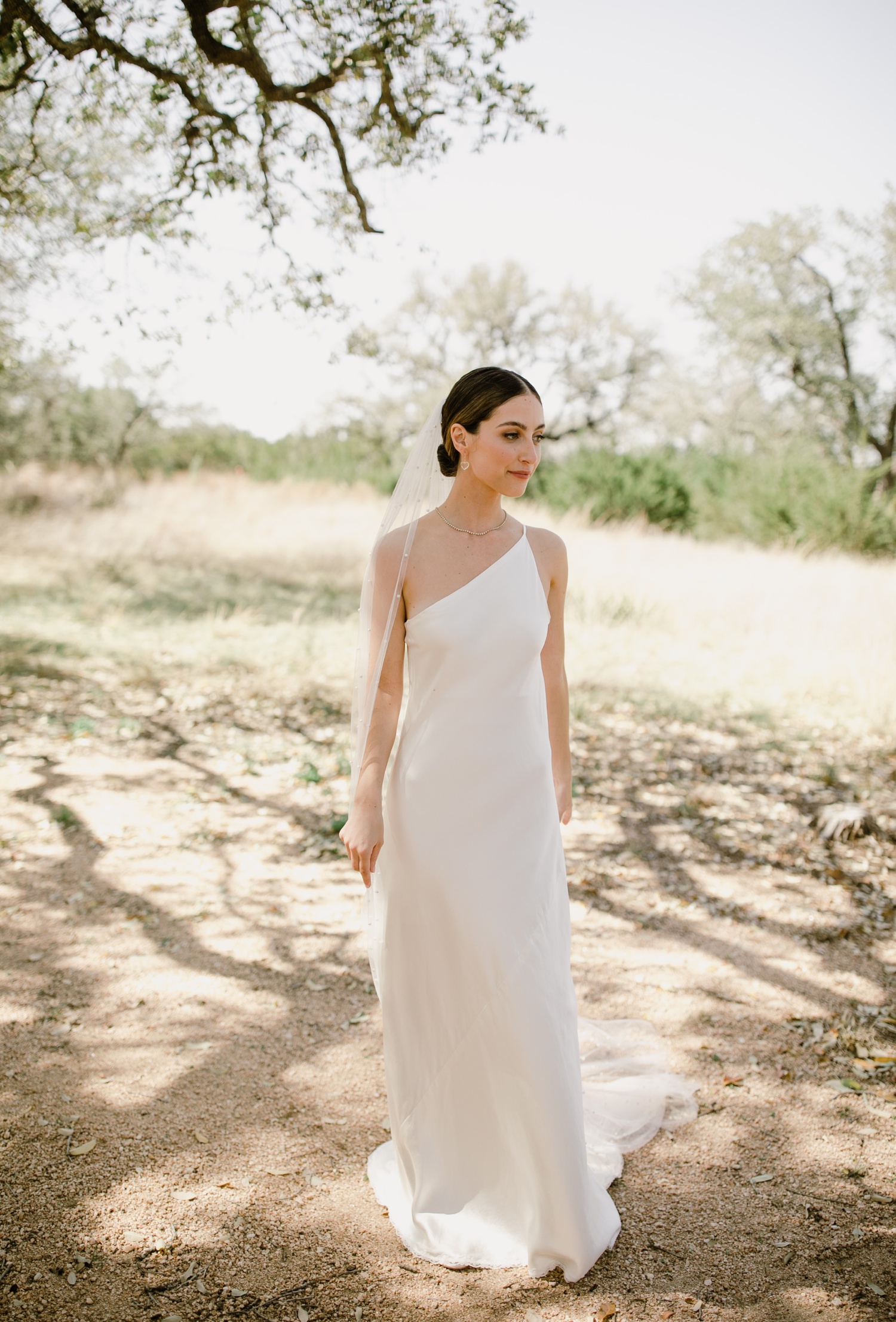 Bride in a one-shoulder slip-style wedding gown by A La Robe