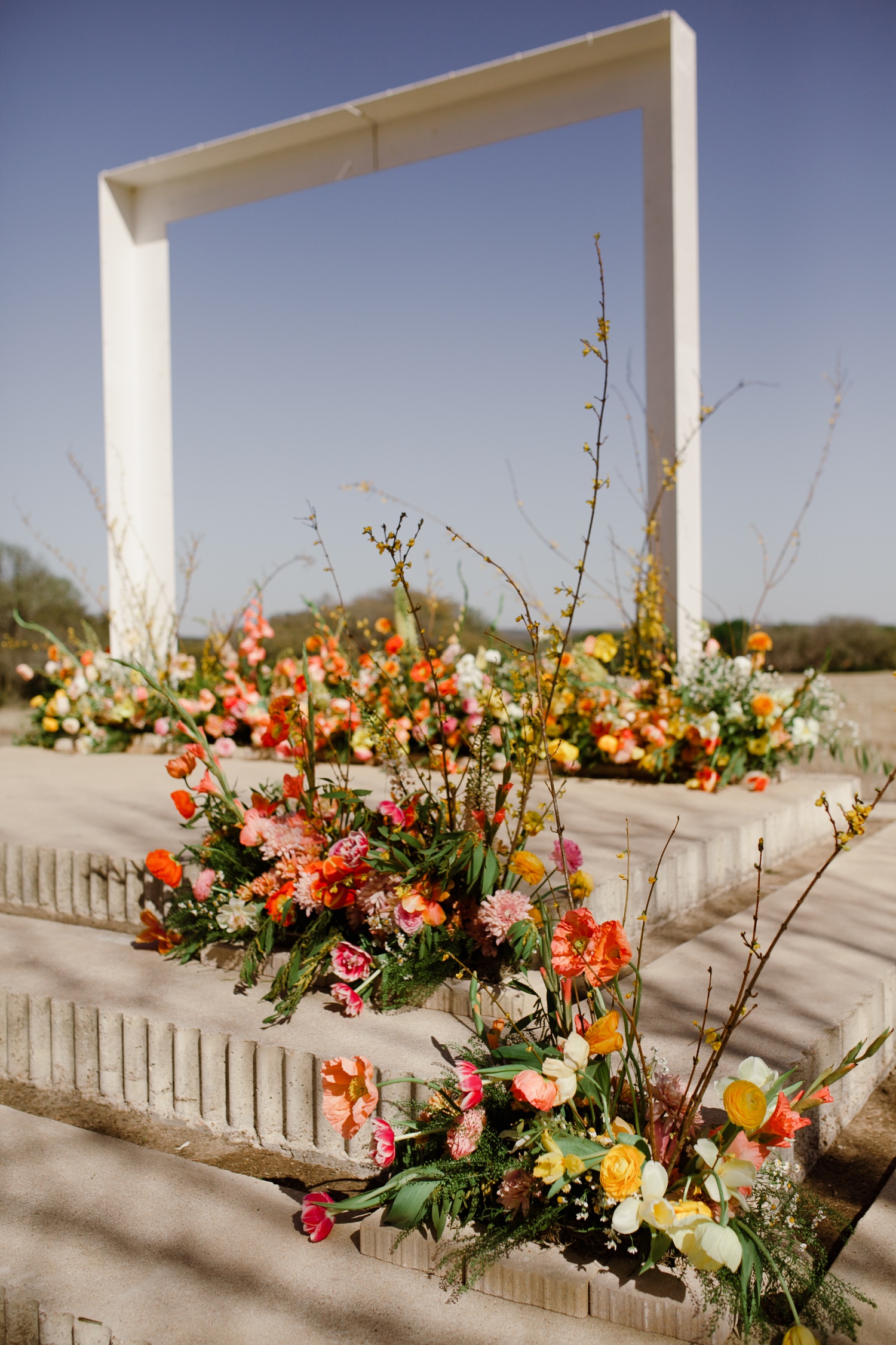 Pink, orange, and yellow florals by Davy Gray for a spring outdoor wedding ceremony