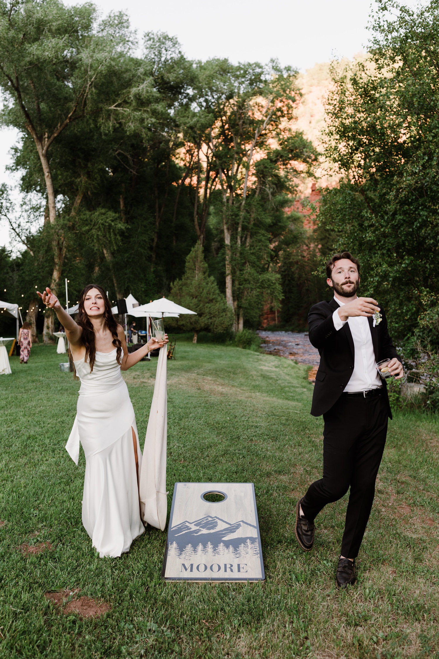 Bride and groom playing cornhole at an outdoor wedding