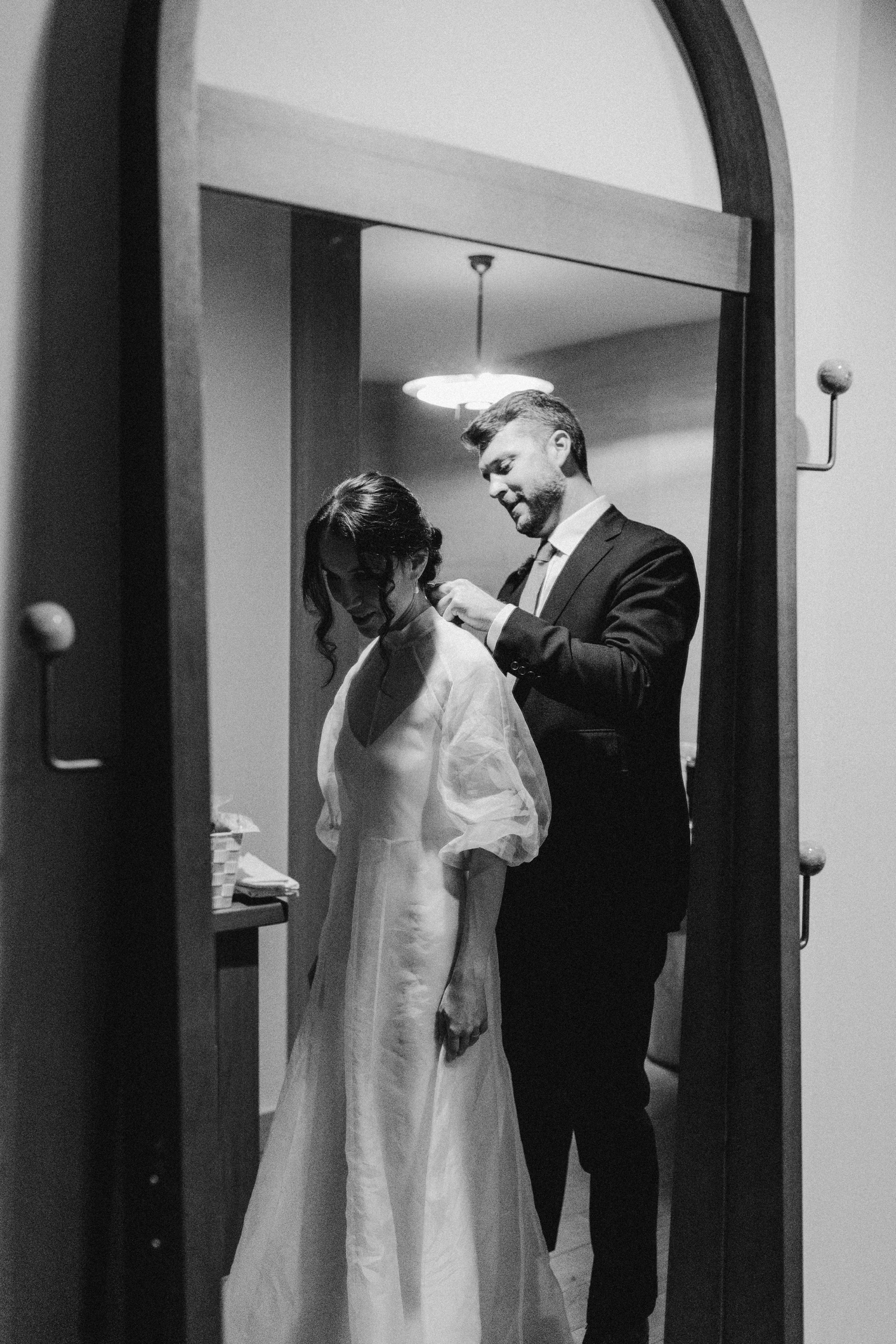 Groom helping his bride change into her wedding reception dress at Austin Proper Hotel