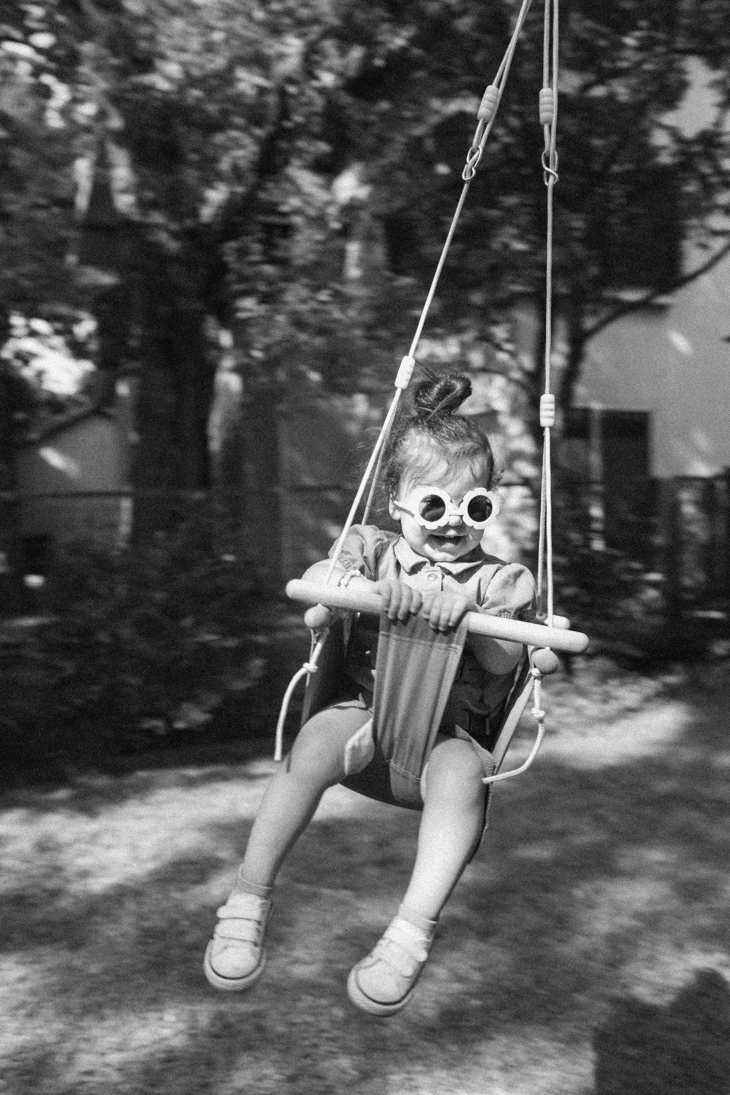 Toddler in a swing wearing flower-shaped sunglasses