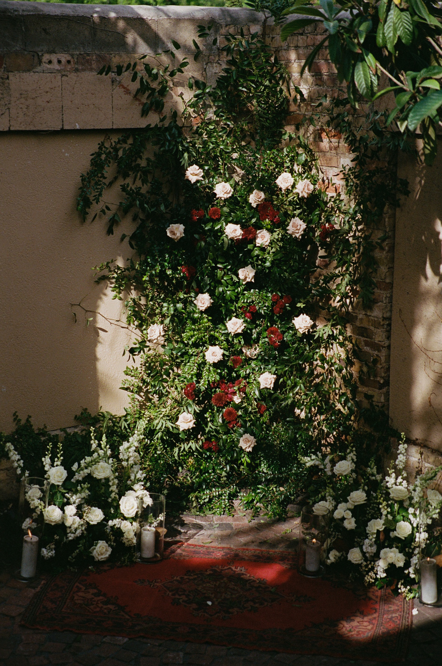 Spring wedding flower wall with blush roses and red chrysanthemums