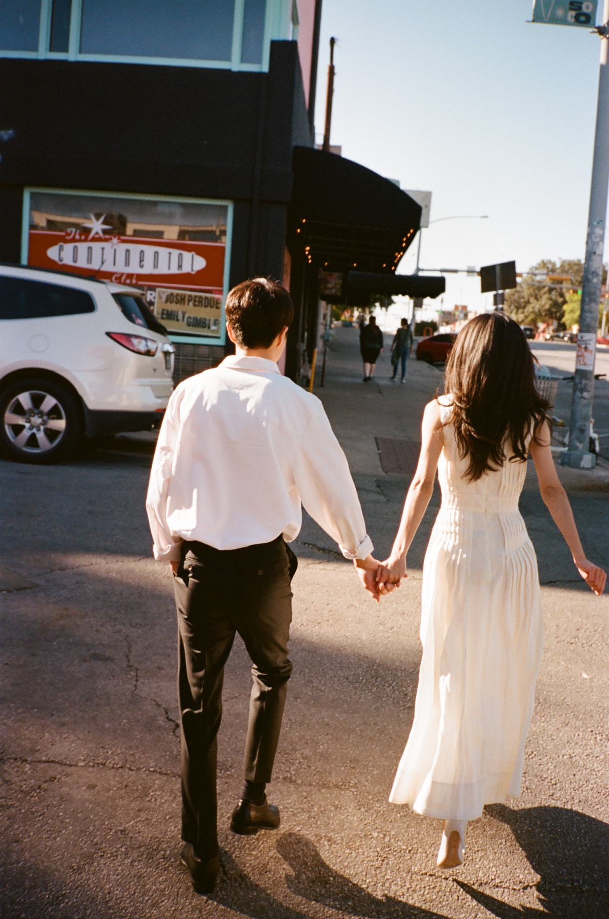 A film photo of a couple walking across a street in South Congress