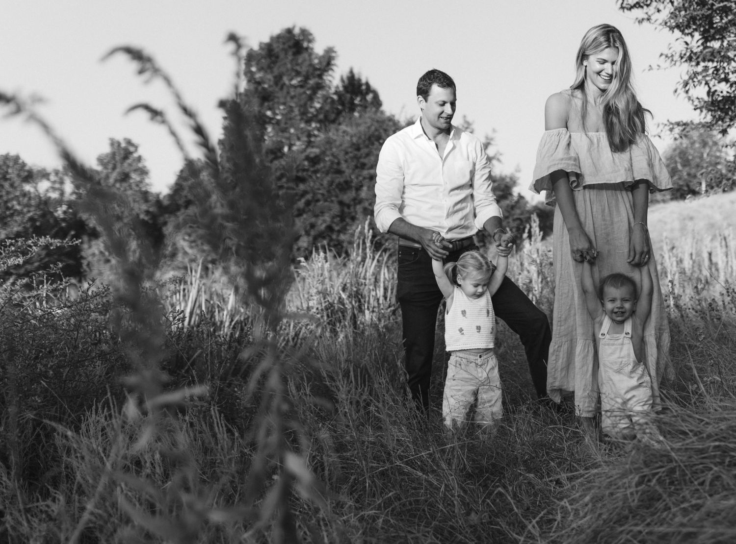 A black and white photo of a family walking though a field 