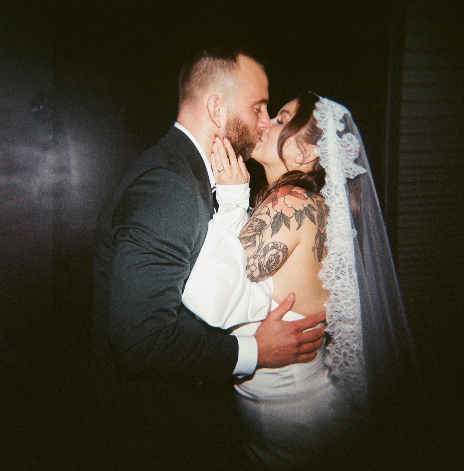 A film photo of a bride and groom kissing after the wedding ceremony