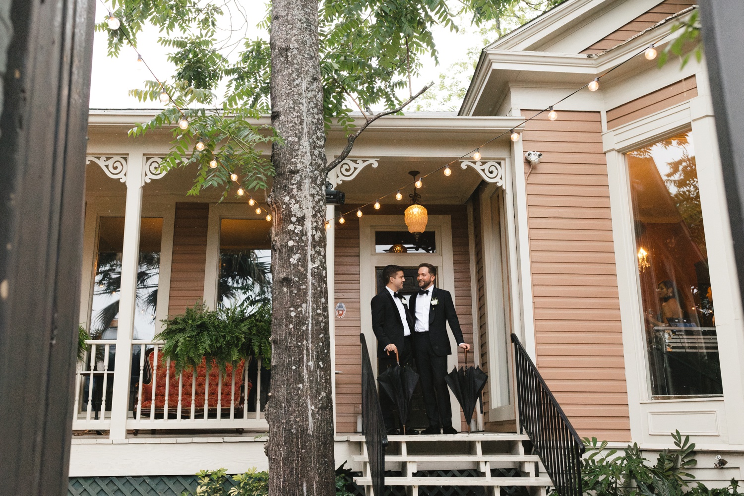 Two grooms standing on the front porch of Justine's Secret House in Austin, TX