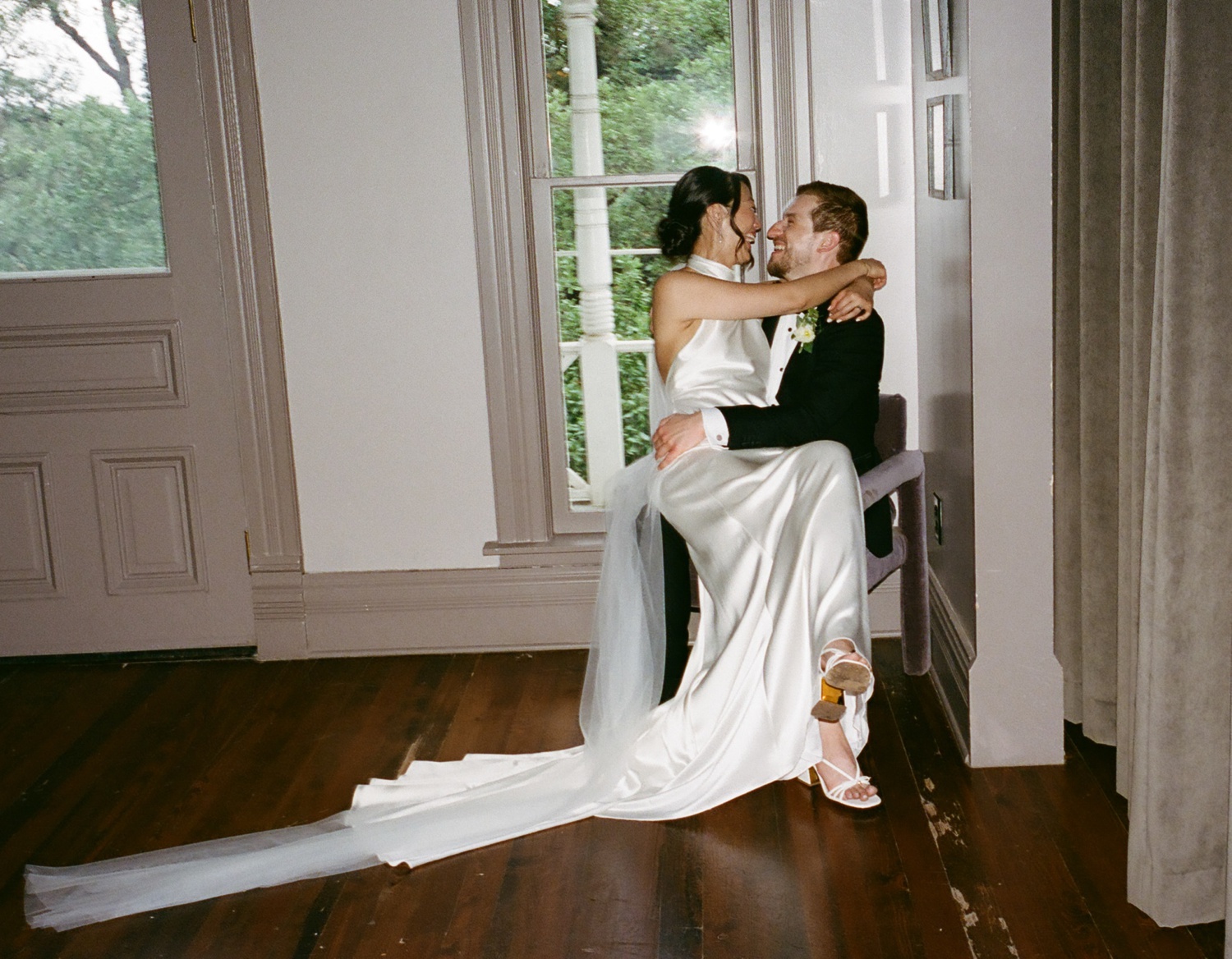 Bride and groom sitting on a chair together and laughing