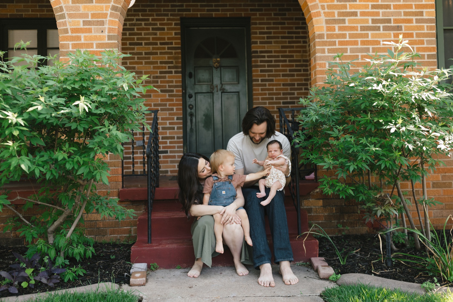 Family of four sitting on the front steps of their house in Austin, TX