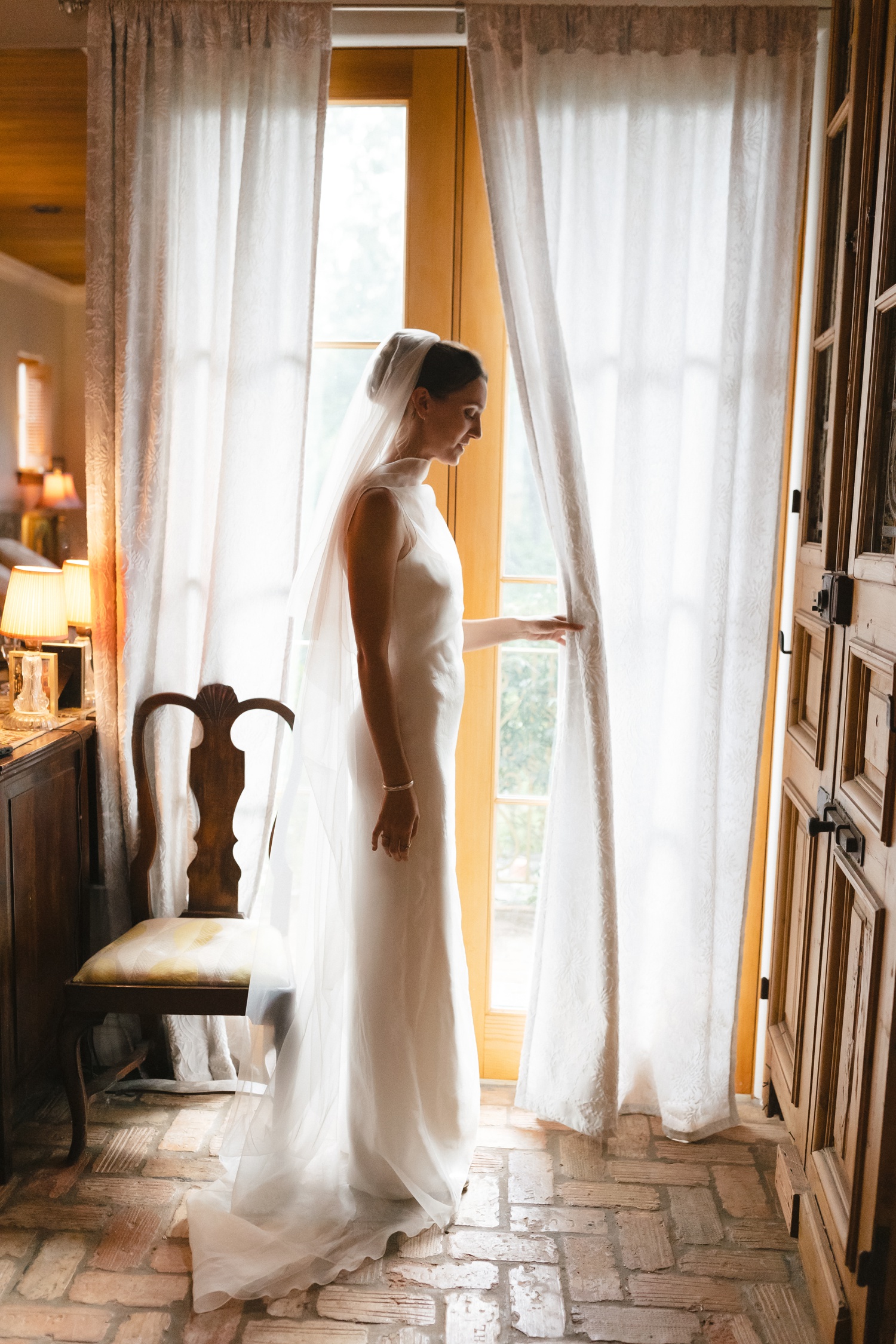 Bride standing next to a window and wearing a sheer wedding veil