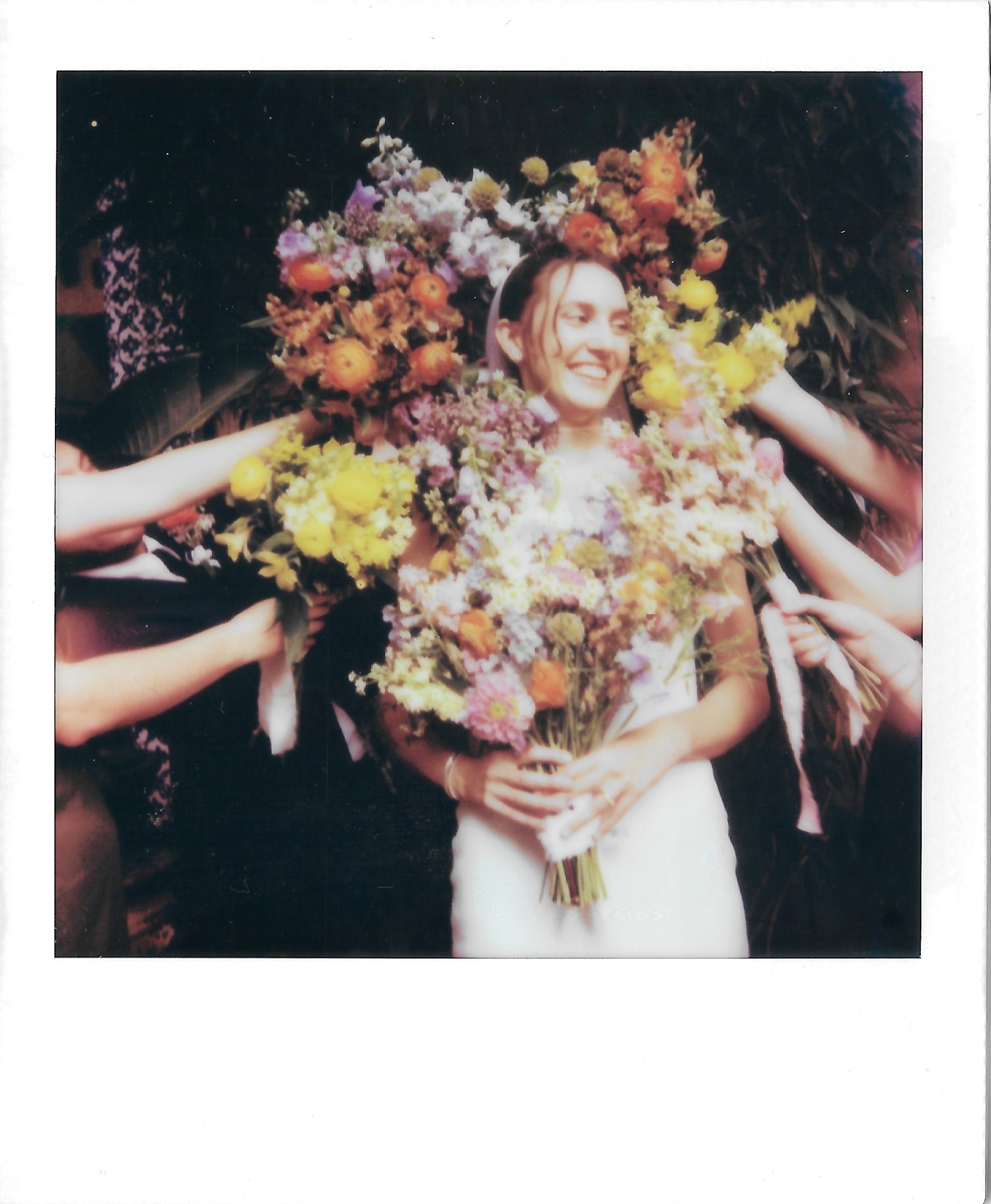 Polaroid of a bride with bouquets of colorful flowers surrounding her head