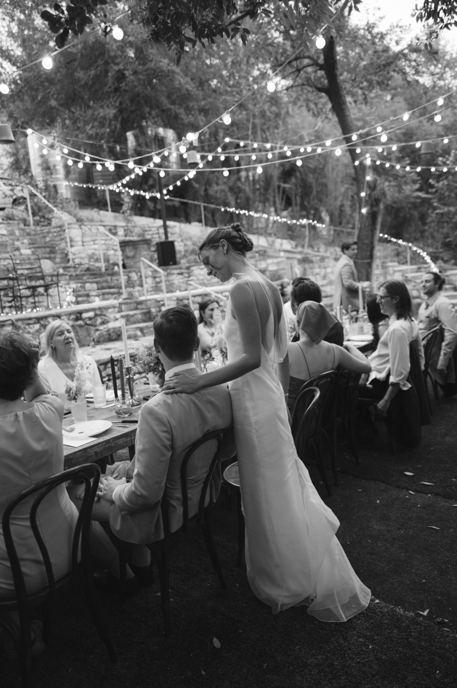 Bride standing behind her groom's chair at their wedding reception