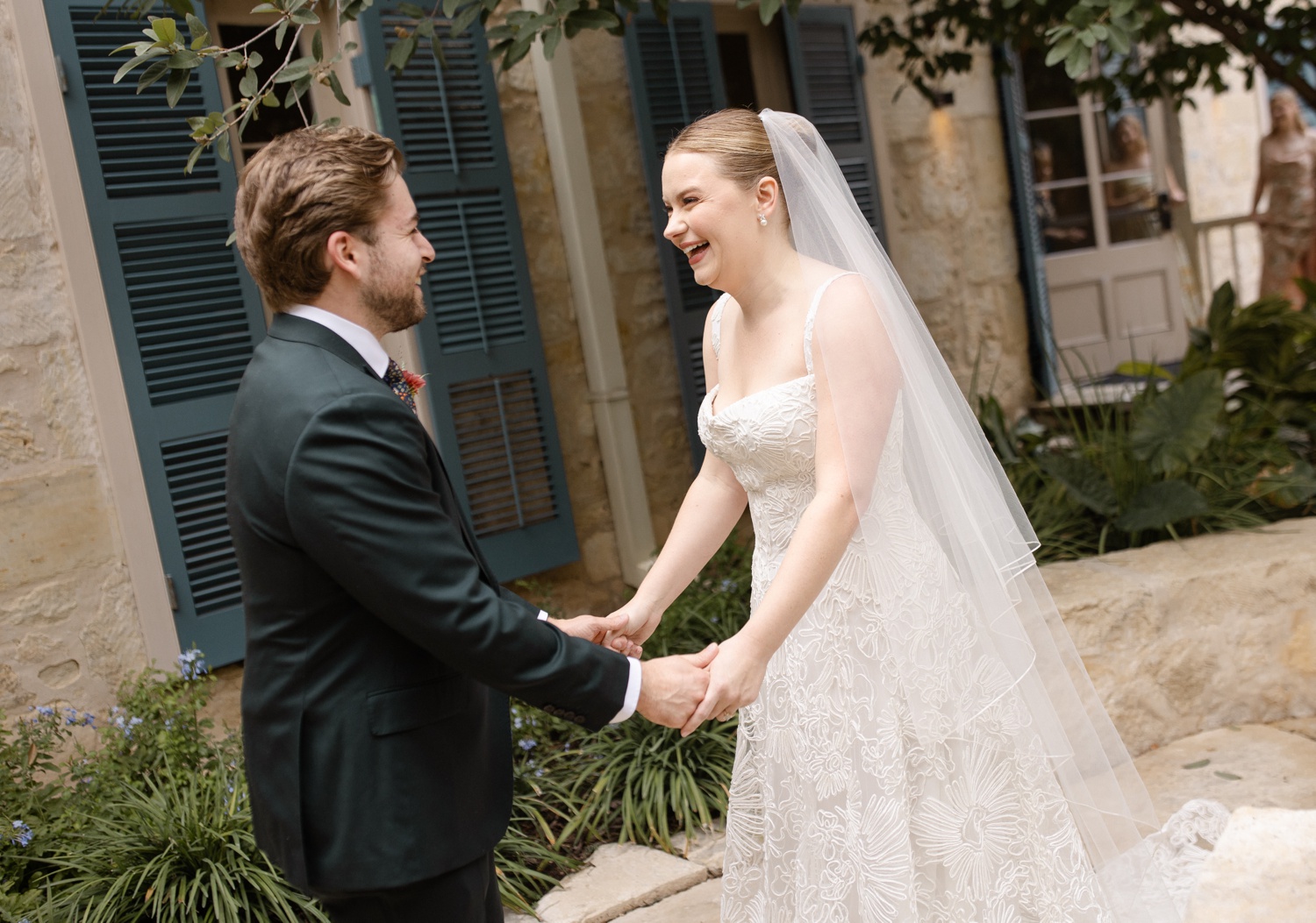 Bride and groom holding hands and smiling at each other after their first look