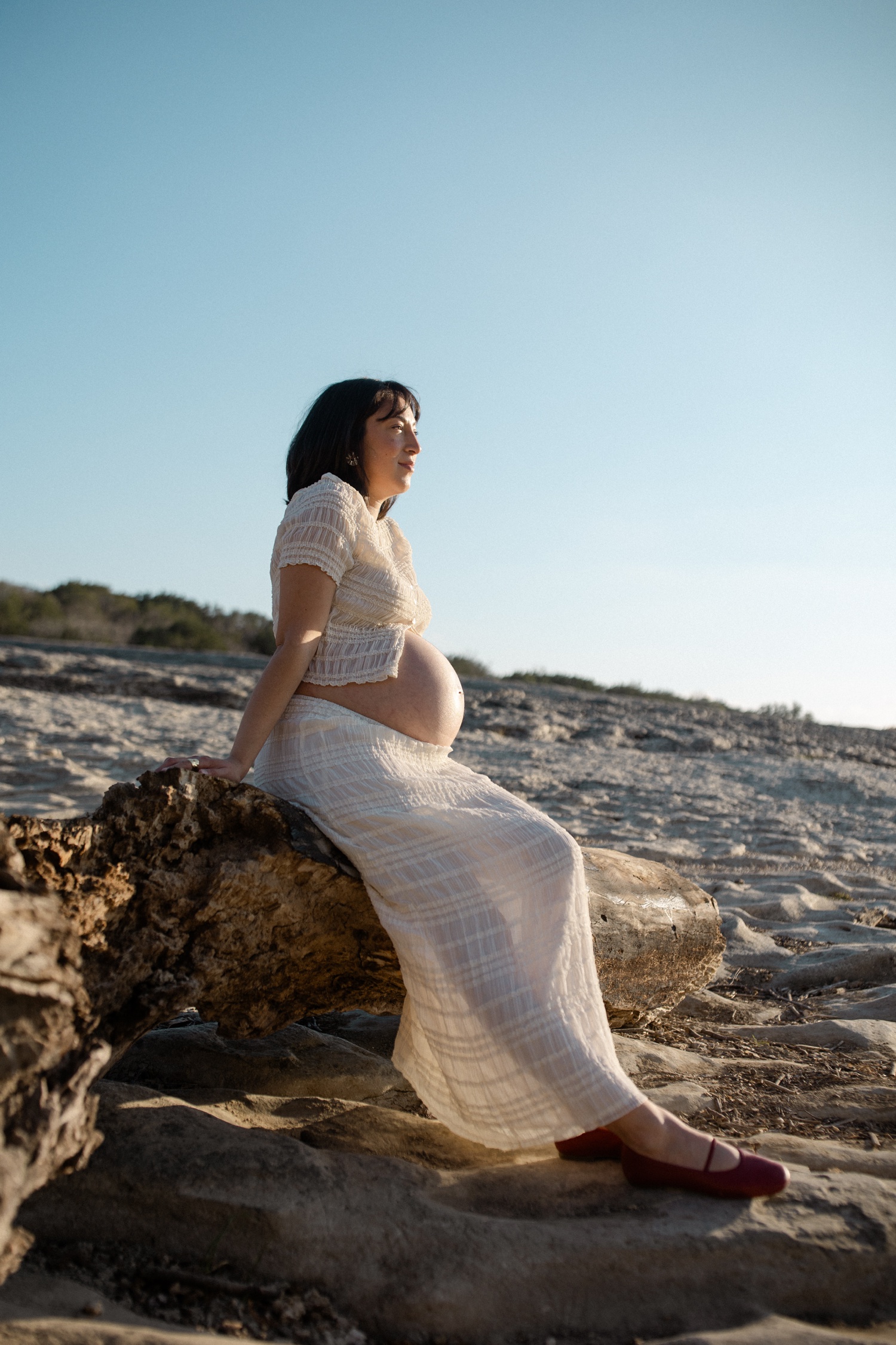 Pregnant woman sitting on a boulder for her maternity session