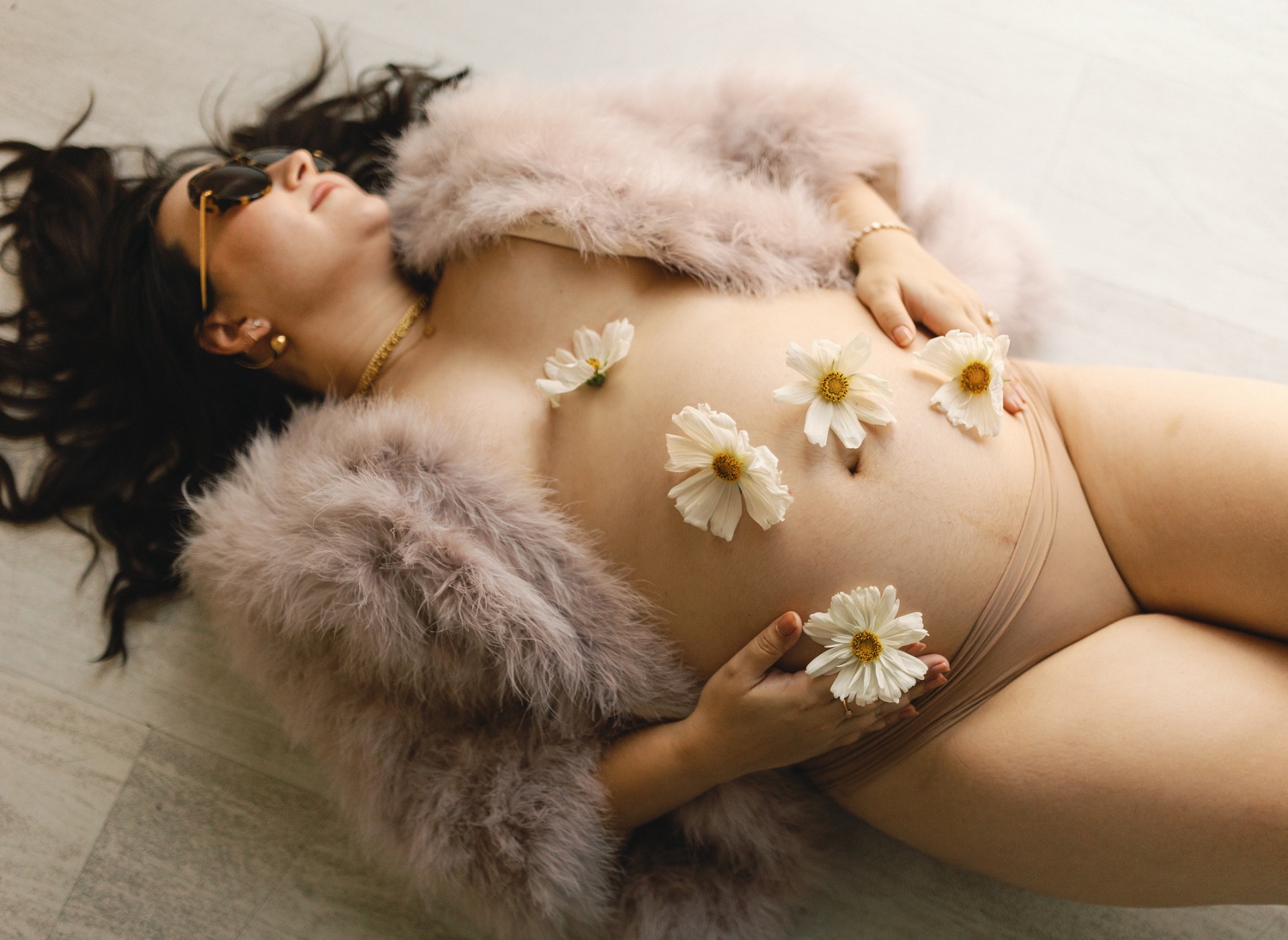 Studio portrait of a pregnant woman lying down with flowers on her baby bump