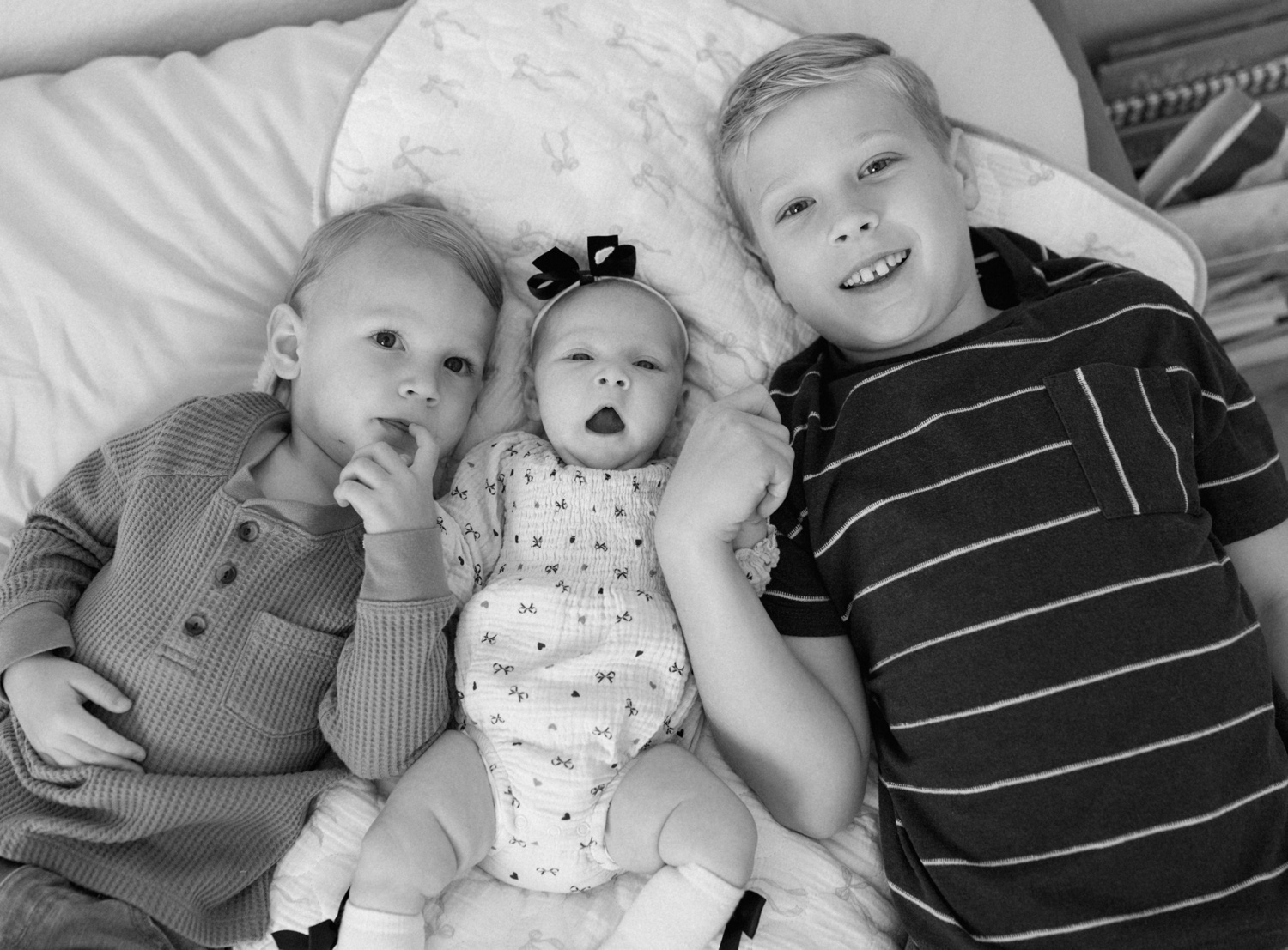 Siblings cuddling with baby sister during an in-home maternity and newborn bundle session